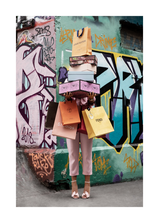 – Photograph of a woman holding shoe boxes and shopping bags in front of a graffiti wall