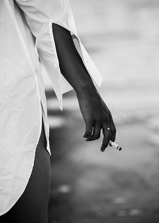 –  Black & white photograph of a girl holding a cigarette by the water 