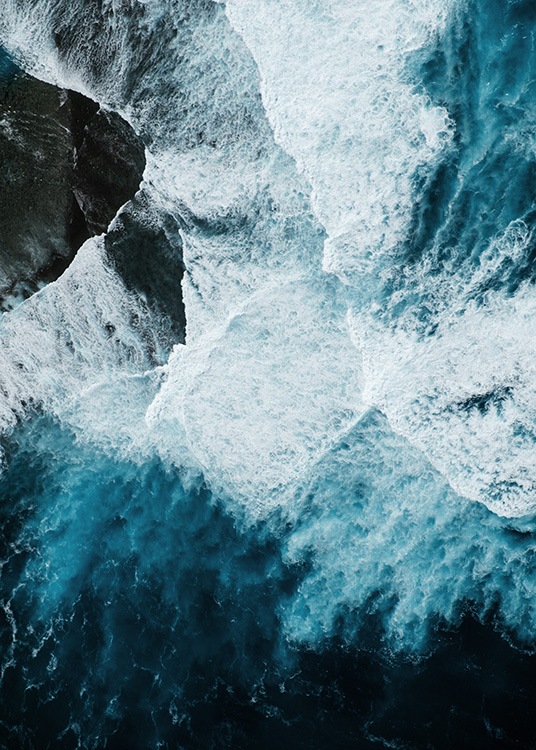 –Ocean waves hitting a rock photographed from above. 