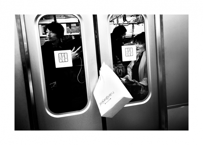 Black and white photograph of shopping bag caught between train doors