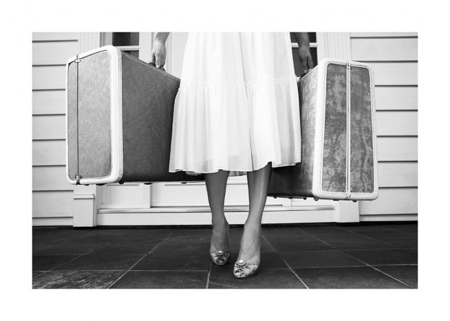  - Black and white photograph of woman wearing a white skirt holding two suitcases 
