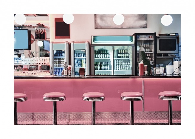  - Photograph from a vintage diner with pink bar chairs in front of a pink bar
