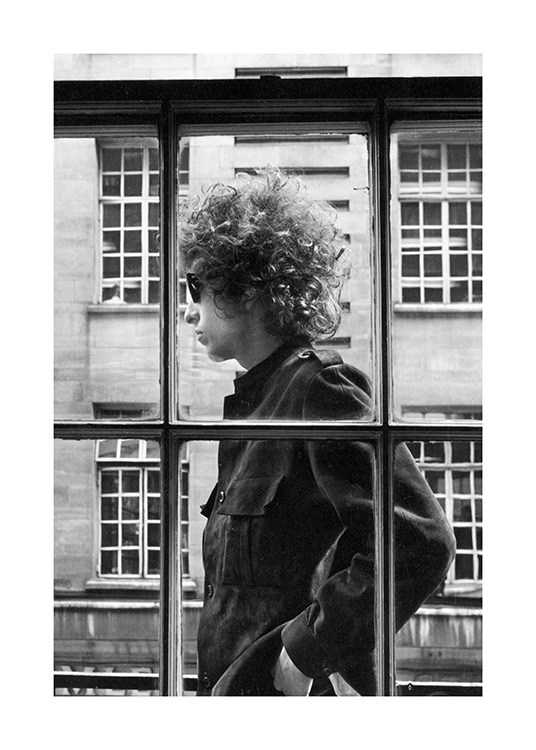  - Photograph of Bob Dylan in black and white, with him standing outside of a window