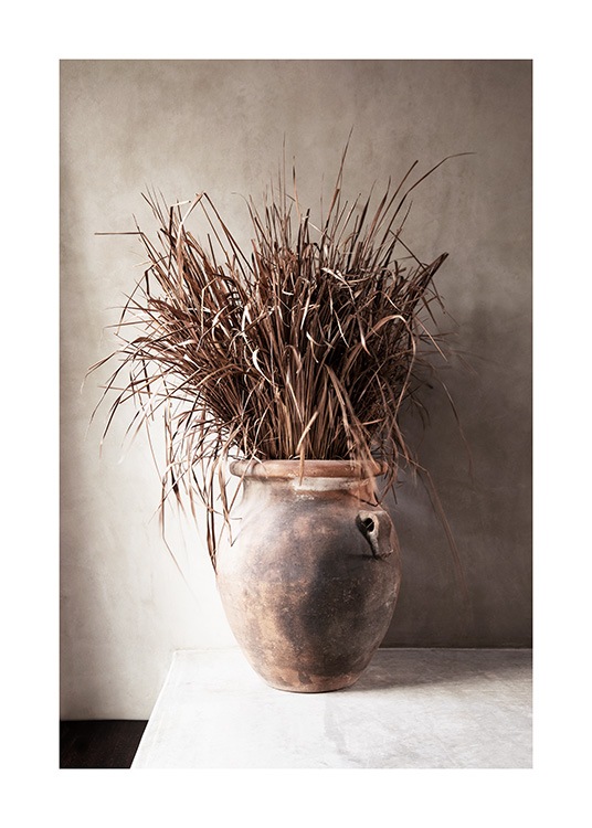  – Photograph of dried, beige grass in a vase against a concrete wall in beige