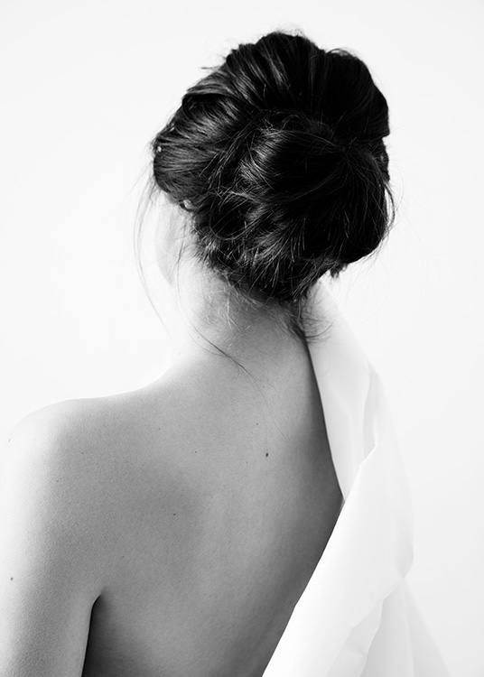  – Black and white photograph of a woman seen from behind, with a naked shoulder and a shirt across the other