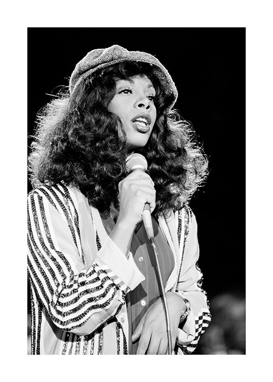  – Black and white photograph of Donna Summers, wearing a hat and striped shirt, holding a microphone