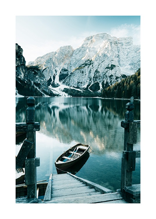  – Photograph of snowy mountains behind a lake with a boat and wooden staircase in the front