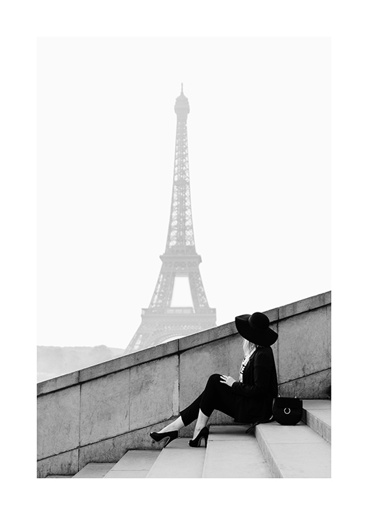  – Black and white photograph of a woman sitting on a staircase with the Eiffel Tower in the background