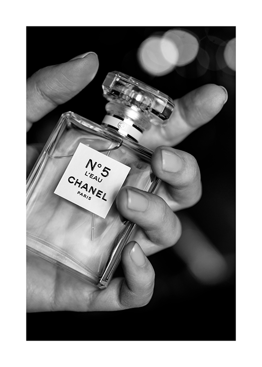  – Black and white photograph of a bottle of Chanel No5 perfume held by a hand