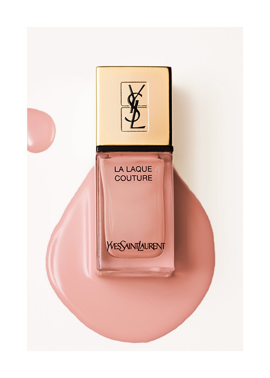  – Photograph of a pink YSL nail polish bottle laying in spilled nail polish, against a light beige background