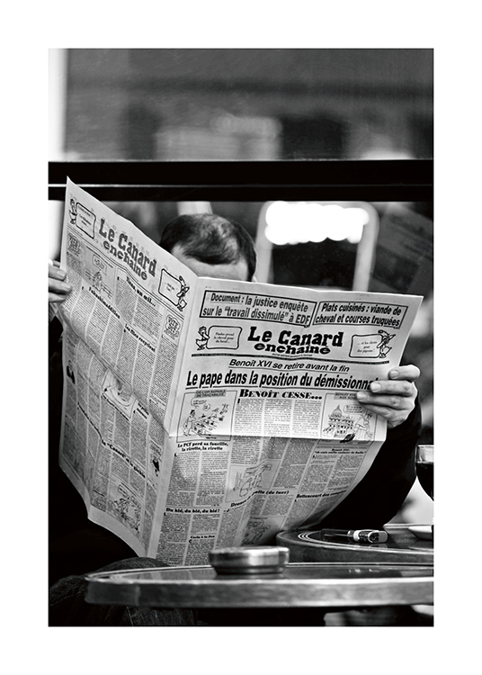  – Black and white photograph of a man reading a newspaper with the title Le Canard enchainé