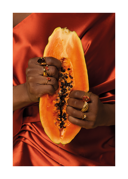 – A woman in a satin dress wearing golden rings squeezing into a papaya fruit