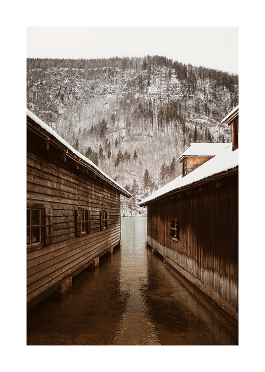  – Photograph of two boathouses in front of a mountain with a snowy forest