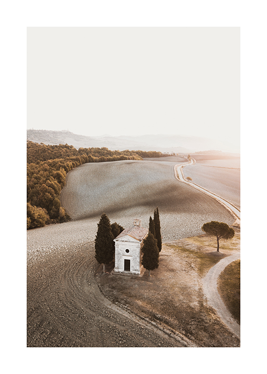 – A photograph of a field and forest landscape with a chapel in it